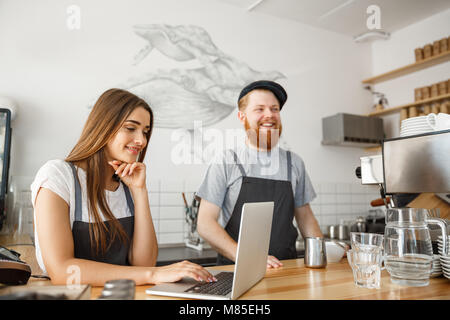 Coffee Business Concept - happy young couple business owners of small coffee shop working and planing on laptop. Stock Photo
