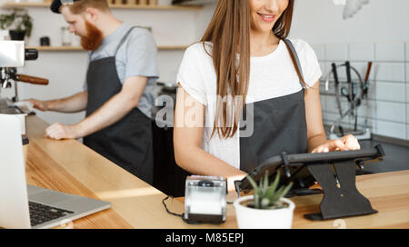 Coffee Business Concept - beautiful caucasian bartender barista or manager Posting order in digital tablet menu at modern coffee shop. Stock Photo