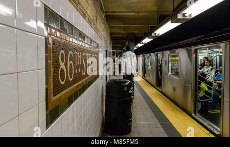 Very tall Man walks along the platform as a train waits to depart from  86th Street subway station,Manhattan, New York City Stock Photo