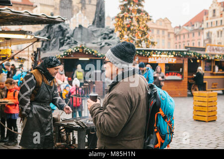 Prague, December 13, 2016: Old Town Square in Prague on Christmas Day. Christmas market in the main square of the city. An elderly tourist drinks hot  Stock Photo