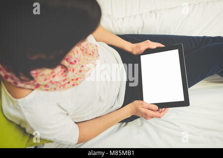 woman using tablet sitting on the bed Stock Photo