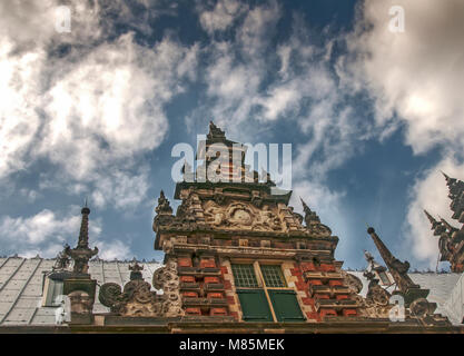 front view of a beautiful old Dutch facade of a house with a cloudy blue sky as background Stock Photo