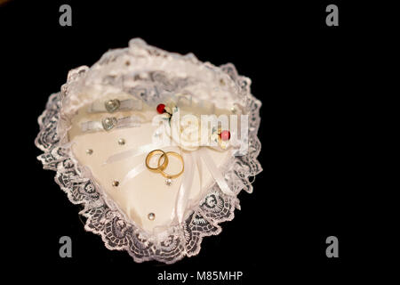 Wedding rings on a heart shaped pillow Stock Photo