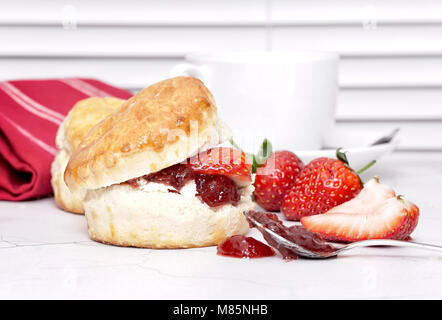 Cream Tea - scones with jam and cream, served with a cup of tea on a white background Stock Photo