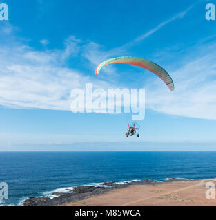 Motorized tandem paraglider against blue sky Stock Photo