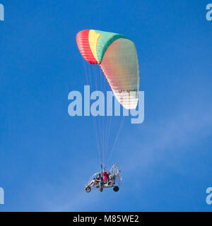 Motorized tandem paraglider against blue sky Stock Photo