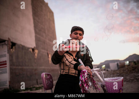 (180315) -- SARPOL-E ZAHAB, March 15, 2018 (Xinhua) -- Paria plays with her brother, Omid, in Sarpol-e Zahab city, western Iran, on March 11, 2018. Paria, 10-year-old Iranian-Kurdish girl, lost her father during a 7.3-magnitude earthquake on Nov. 12, 2017. Now, she is living with her mother and only brother in a conex home, as their house was completely destroyed during the tremor. She has had her father as the 'hero' of her life, she sobbed. Asked what her top dream in her life is, she dropped her head saying in low voice: 'I cannot think of another disaster like 'this' for anybody in the wor Stock Photo