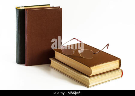 On a white background there are several books, glasses lie on the book Stock Photo