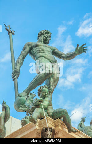 Detail close up of 1500s Bologna Neptune statue-fountain of Bologna city in Italy. Restored in 2018 and located in Nettuno square of Bologna city center. Vertical lower ground view with blue sky. Stock Photo