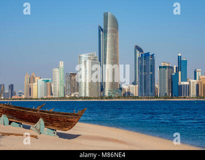 Traditional boat in the Heritage Village with city skyline in the background, Abu Dhabi, United Arab Emirates Stock Photo