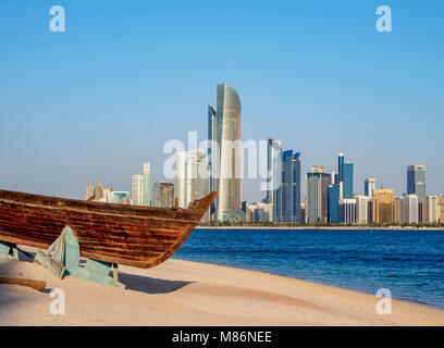 Traditional boat in the Heritage Village with city skyline in the background, Abu Dhabi, United Arab Emirates Stock Photo