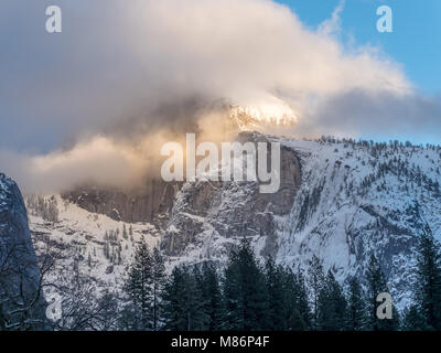 Sunrise Sun Rays Shining on Low White Clouds over the Tall Mountains in Yosemite Stock Photo
