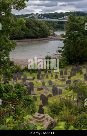 Church graveyard and suspension bridge at Menai Straits, Anglesey, North Wales coast Stock Photo