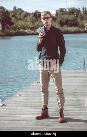 Stylish young handsome man with fancy sunglasses posing at the pier Stock Photo
