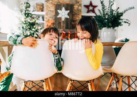 Boy and girl sitting at the dining table messing about at Christmas Stock Photo
