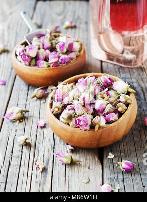 small dry buds of roses, tea, karkade, in wooden bowls on wood table, selective focus Stock Photo