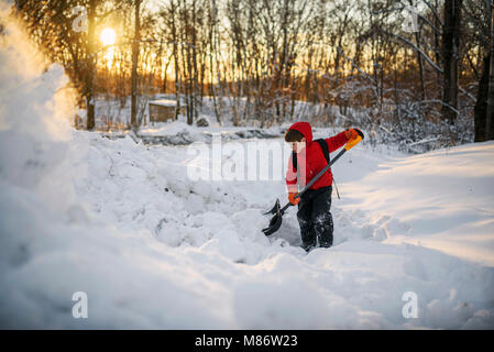 Boy shoveling snow in the garden Stock Photo