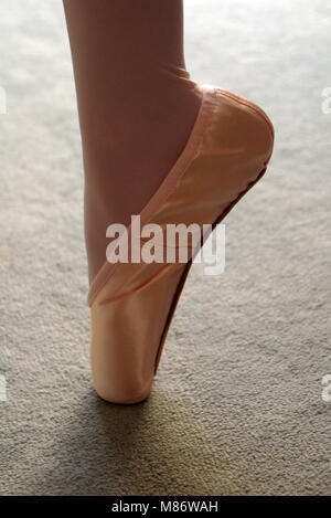 Girl's foot in satin ballet pointe shoe Stock Photo