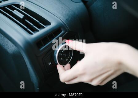 Woman turning on car headlights. Modern car interior Stock Photo