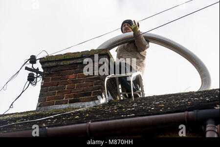 An engineer installs flue pipe down a chimney to ensure safety of a log burner's operation. Stock Photo