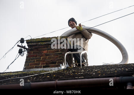 An engineer installs flue pipe down a chimney to ensure safety of a log burner's operation. Stock Photo