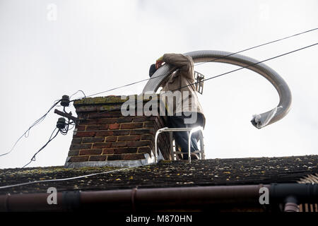 An engineer installs flue pipe down a chimney to ensure safety of a log burner's operation. Stock Photo