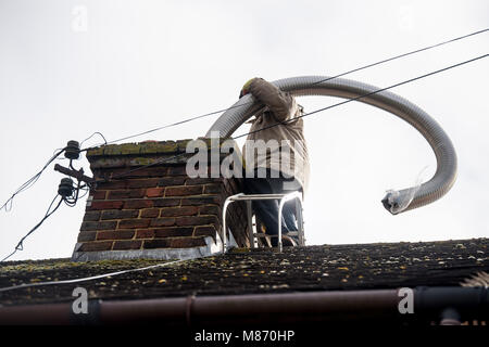 An engineer installs flue pipe down a chimney to ensure safety of a log burner's operation. Stock Photo