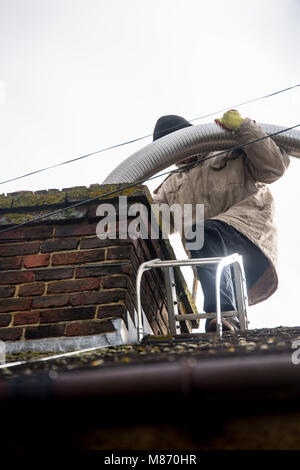 An engineer installs flue pipe down a chimney to ensure safety of a log burner's operation. Stock Photo