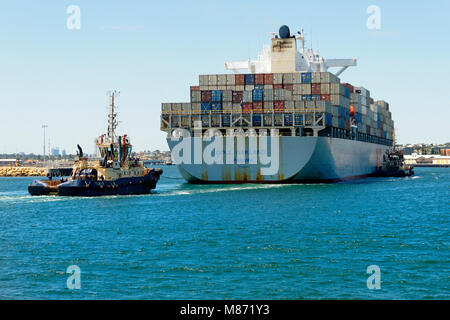 Container ship OOCL OAKLAND (Panama) with tug boats alongside  entering Fremantla harbour, Fremantle, Western Australia Stock Photo