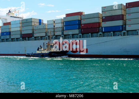 Container ship OOCL OAKLAND (Panama) with tug boat alongside  entering Fremantla harbour, Fremantle, Western Australia Stock Photo