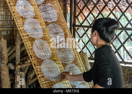 A Vietnamese woman moves bamboo drying racks on which she is drying hand made rice paper. Stock Photo
