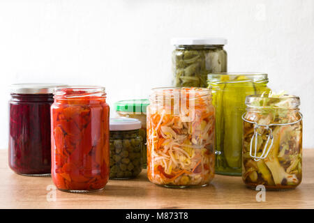 Fermented preserved vegetables in jar on wooden table. Stock Photo