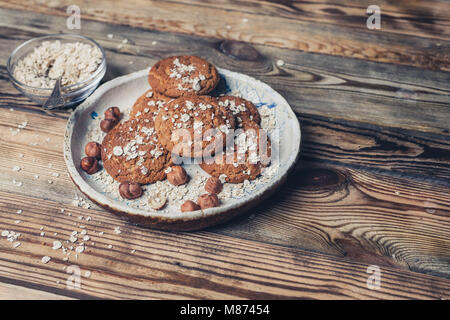 Pile of homemade oatmeal cookies on white ceramic plate on a wooden background Stock Photo