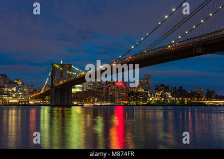 The Brooklyn Bridge and Brooklyn lit up at dusk with the reflections in the East River, New York, USA Stock Photo