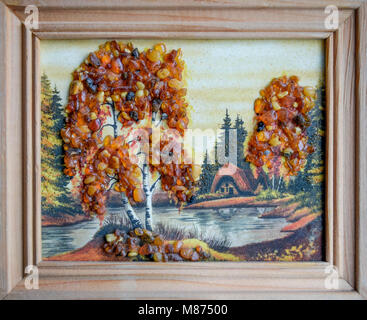 Picture of an amber stone. Crafts made of amber. Landscape house by the river. Stock Photo