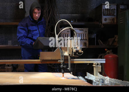 St. Petersburg, Russia - May 30, 2017: The worker cuts the steel plate using PC-based CNC machines with control plasma cutting function. Stock Photo