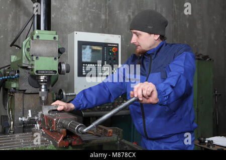 St. Petersburg, Russia - May 30, 2017: Factory worker set up metal working part into cnc punching, milling machine. Stock Photo