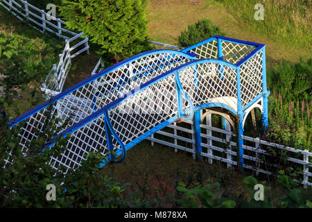 Sunlit vintage iron pedestrian bridge over a railway track Stock Photo