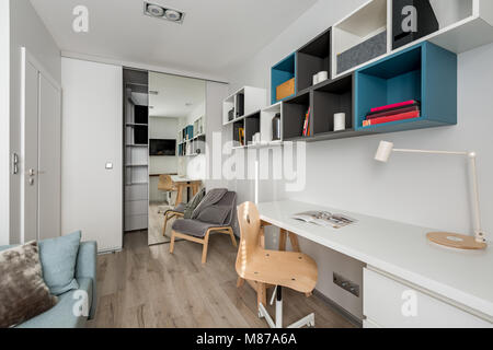 Modern office room with white desk, wooden chair and wall bookshelves Stock Photo