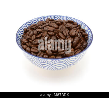 Roasted coffee beans in a blue and white ceramic bowl, on a white background Stock Photo