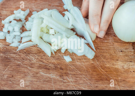 Woman hands slicing onions on a wooden cutting board Stock Photo