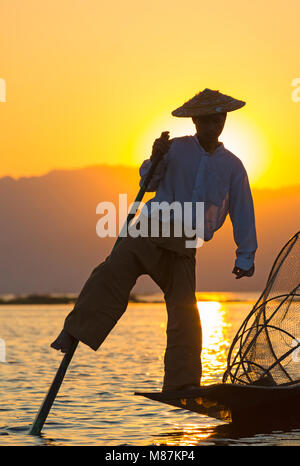 Intha leg rowing fishermen at sunset at Inle Lake,  Myanmar (Burma), Asia in February - fisherman standing on one leg Stock Photo