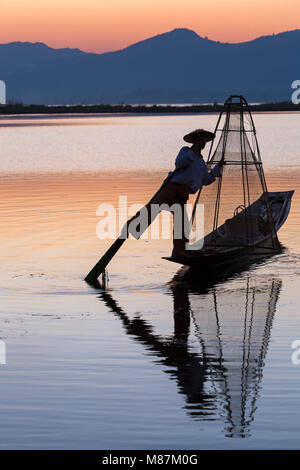 Inle Lake Myanmar Intha leg rowing fishermen at sunset at Inle Lake, Myanmar (Burma), Asia in February - fisherman standing on one leg Stock Photo