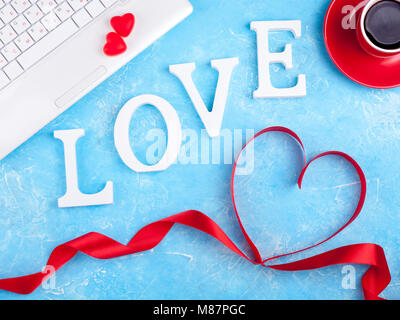 Valentines background with red heart, coffee cup and laptop. Valentines Day greeting card. Female workplace. Top view Stock Photo