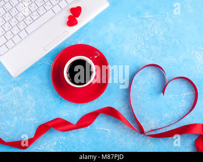 Valentines background with red heart, coffee cup and laptop. Valentines Day greeting card. Female workplace. Top view Stock Photo