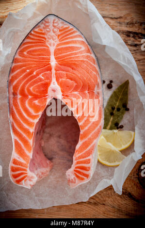Raw salmon fish steak with lemon and spices on wooden rustic background. Fresh fish. Top view Stock Photo