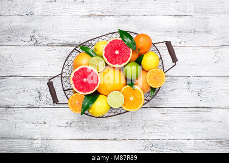 Fresh citrus fruits in basket. Orange, grapefruit, lemon, lime, tangerine. Assorted fresh citrus fruits with leaves. Top view and copy space Stock Photo