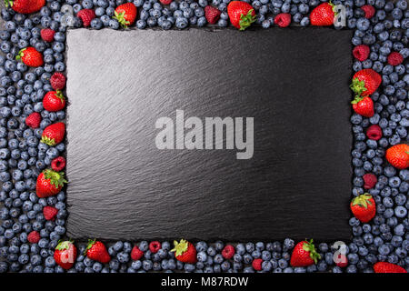 Frame with berries assorted mix of strawberry, blueberry, raspberry. Various fresh summer berries on black background. Top view Stock Photo
