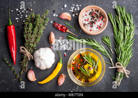 Herbs and spices. Rosemary, thyme, chili, garlic, olive oil, salt and pepper on dark table. Cooking ingredients. Top view and copy space for your reci Stock Photo