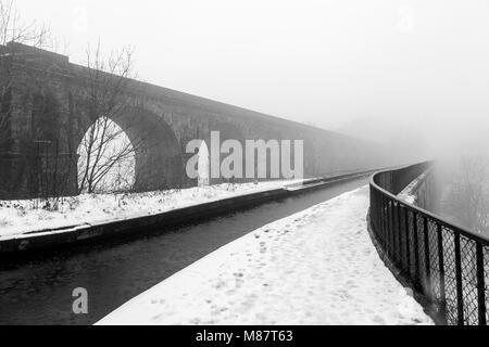 The Chirk aqueduct and railway viaduct disappear into the mist on the Llangollen canal during late winter Stock Photo